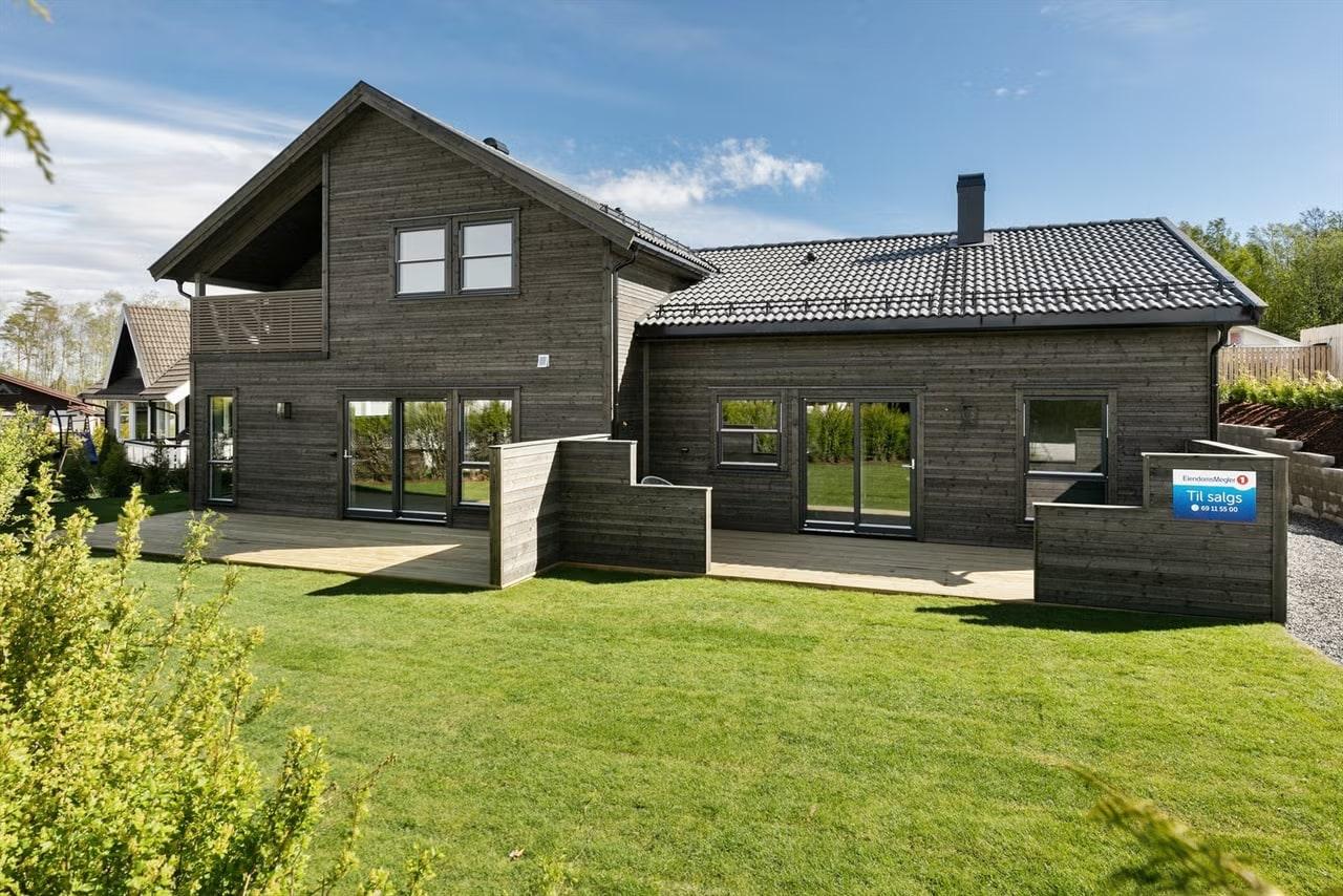 Enebolig i mørkt tre med stor plen